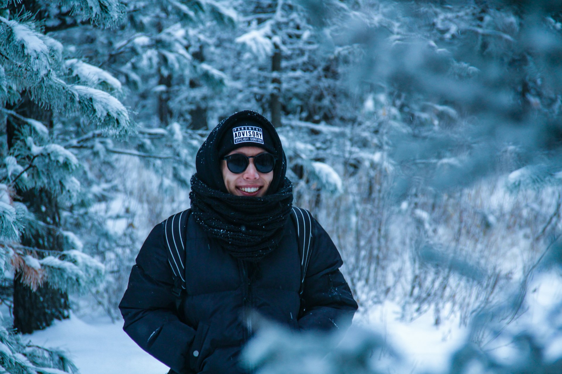 smiling man standing near snow-covered trees